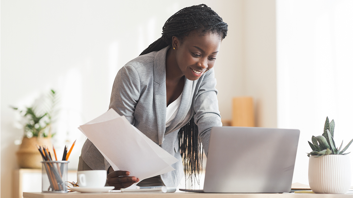 women holding a piece of paper and looking at computer